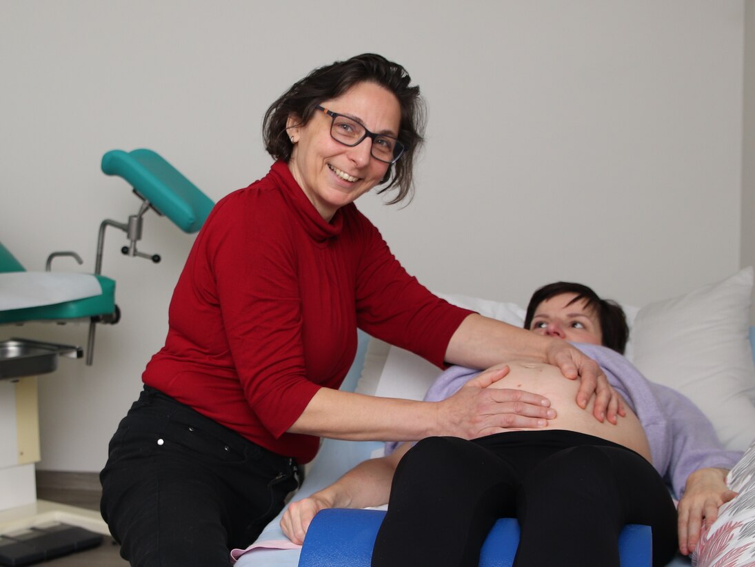 Die Hebamme untersucht eine hochschwangere Patientin auf der Liege