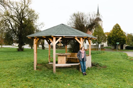 ein Frau steht vor dem Holzpavillon in der Ortsmitte