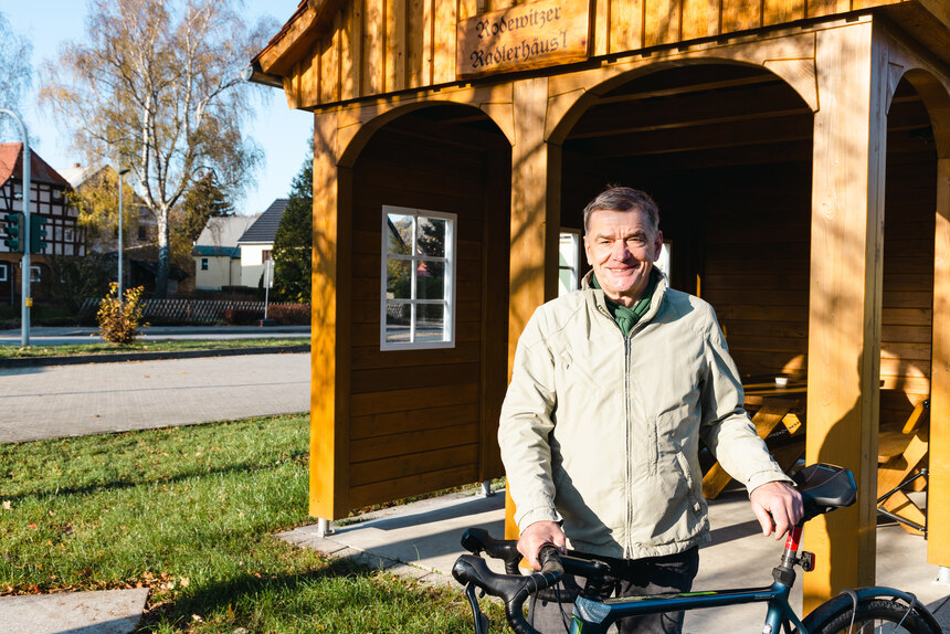 Mann mit Fahhrad steht vor der Rasthütte im Baustil eines Oberlausitzer Umgebindehauses 