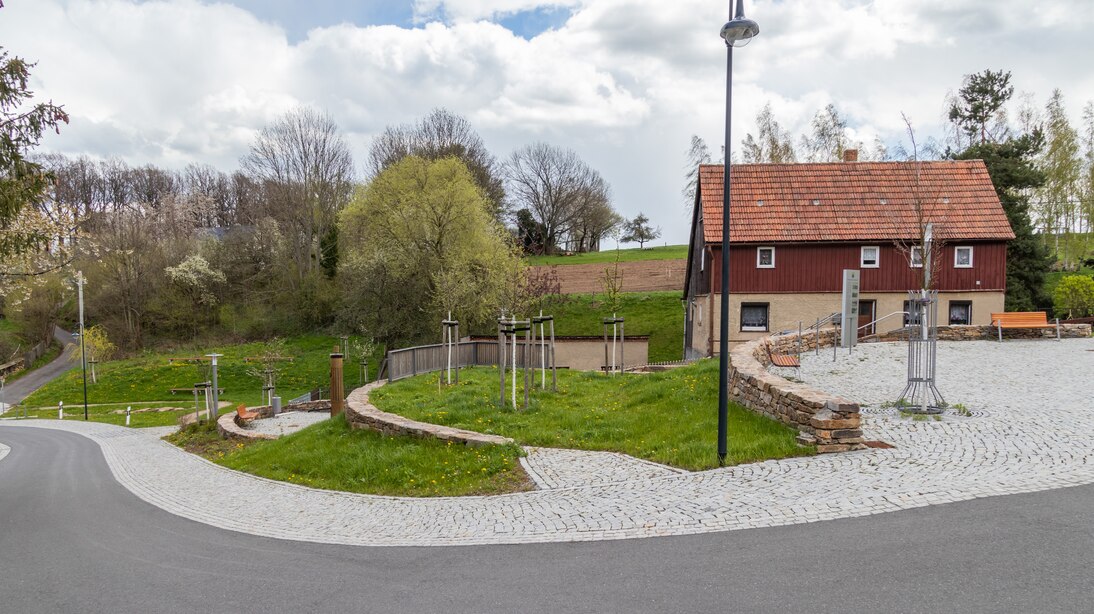 terrassierte Aufenthaltsebenen an Stelle eines abgerissenen Hauses zwischen der Straße und der Treppe, Straße mit grauem Belag, optisch vom Fußweg und Aufenthaltsebenen durch hellgrauen Granitpflaster abgesetzt