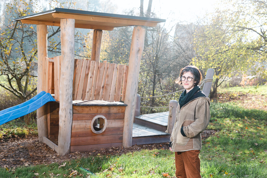 Die Pfarrerin steht im Garten der Begegnung neben einem Spielgerät mit Rutsche