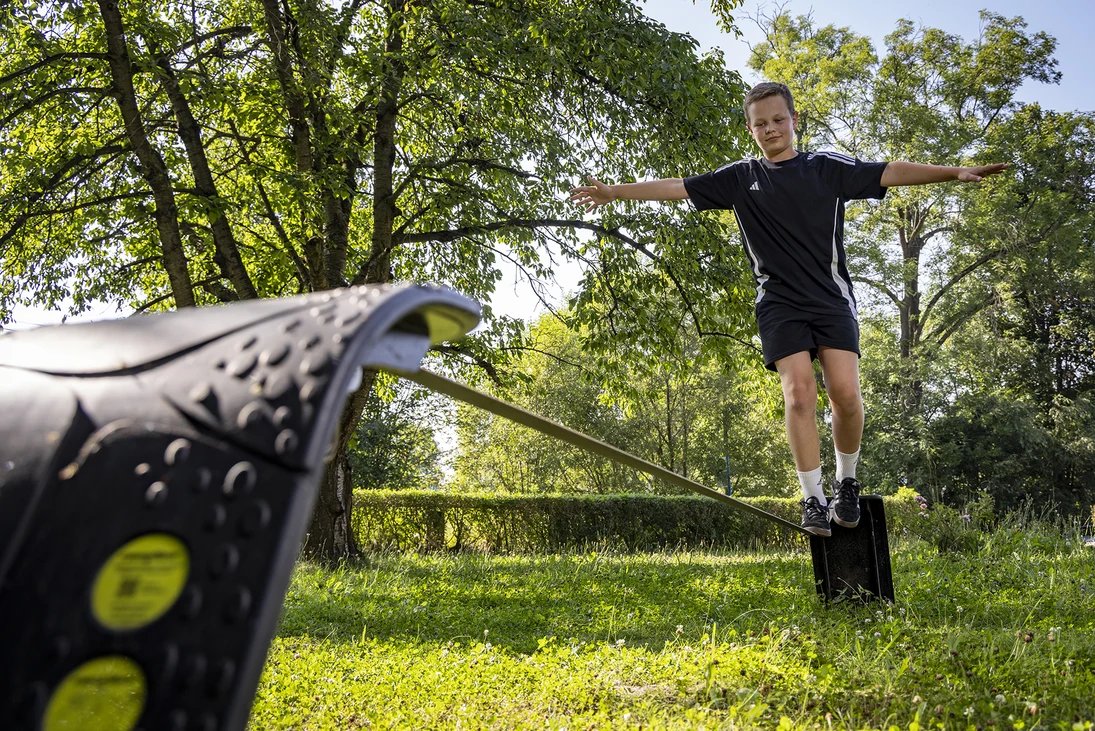 ein Junge balanciert auf einer Slackline im Freien