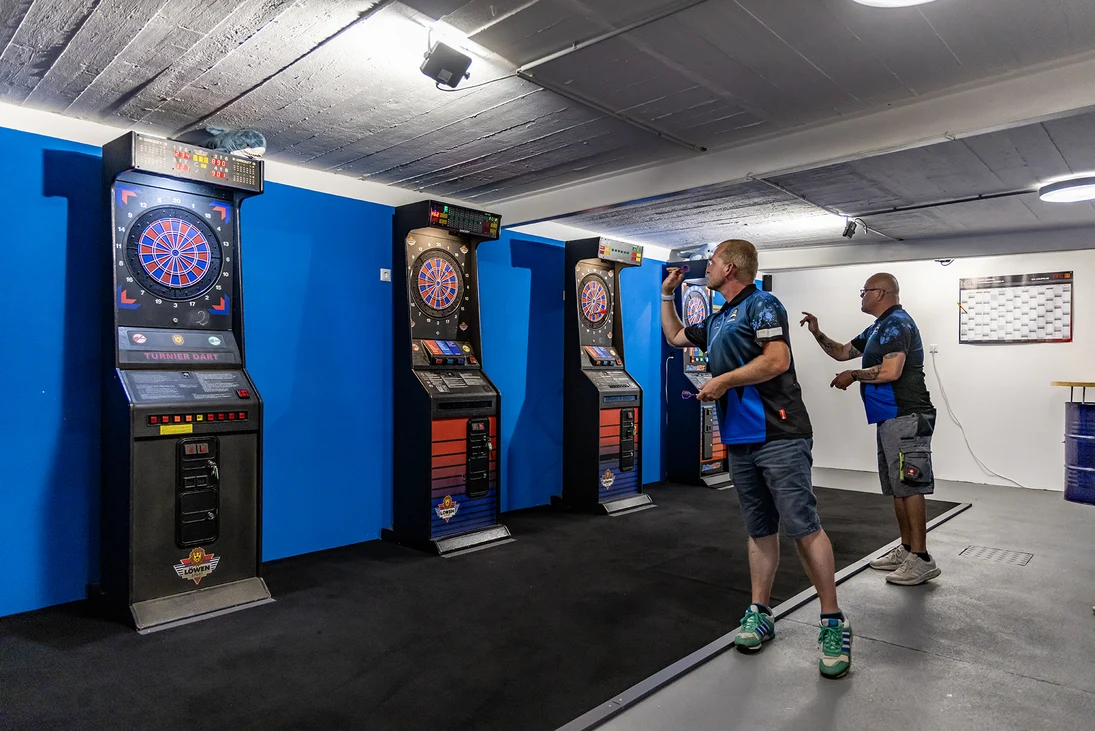 zwei Männer werfen Pfeile auf elektronische Dartscheiben