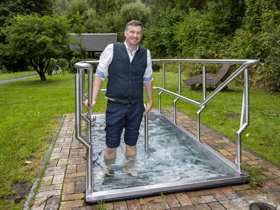 ein Mann steht mit hochgekrempelten Hosen im Wasserbecken
