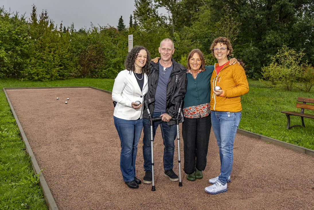 vier Menschen stehen auf einer Boule-Bahn