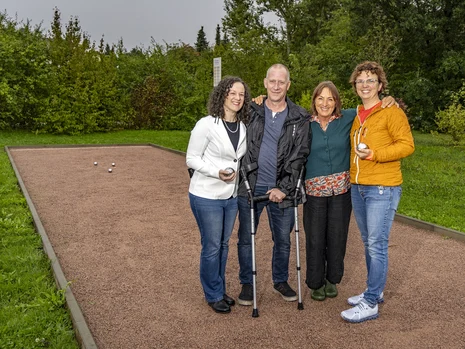 vier Menschen stehen auf einer Boule-Bahn