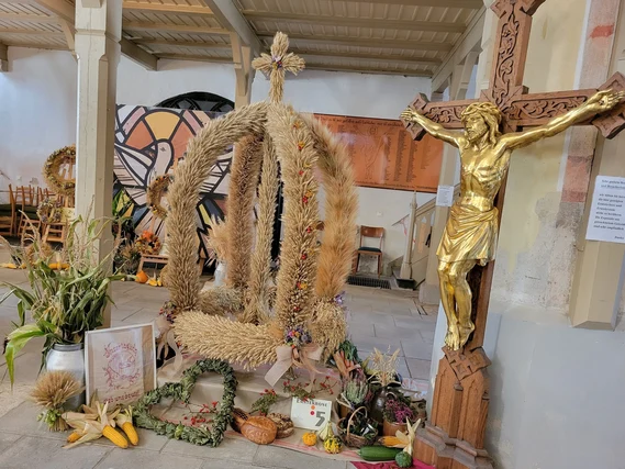 Große Erntekrone neben goldener Christusdarstellung am Kreuz