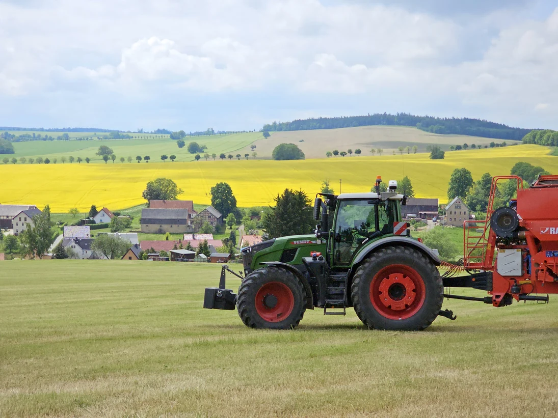 Traktor vor Rapsfeldern