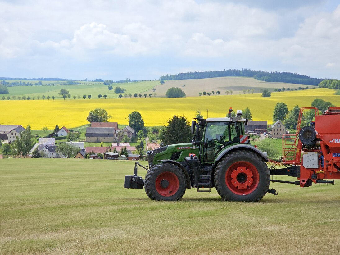 Traktor vor Rapsfeldern