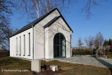 Zu sehen ist ein Eingang zu einer weißen Trauerhalle.