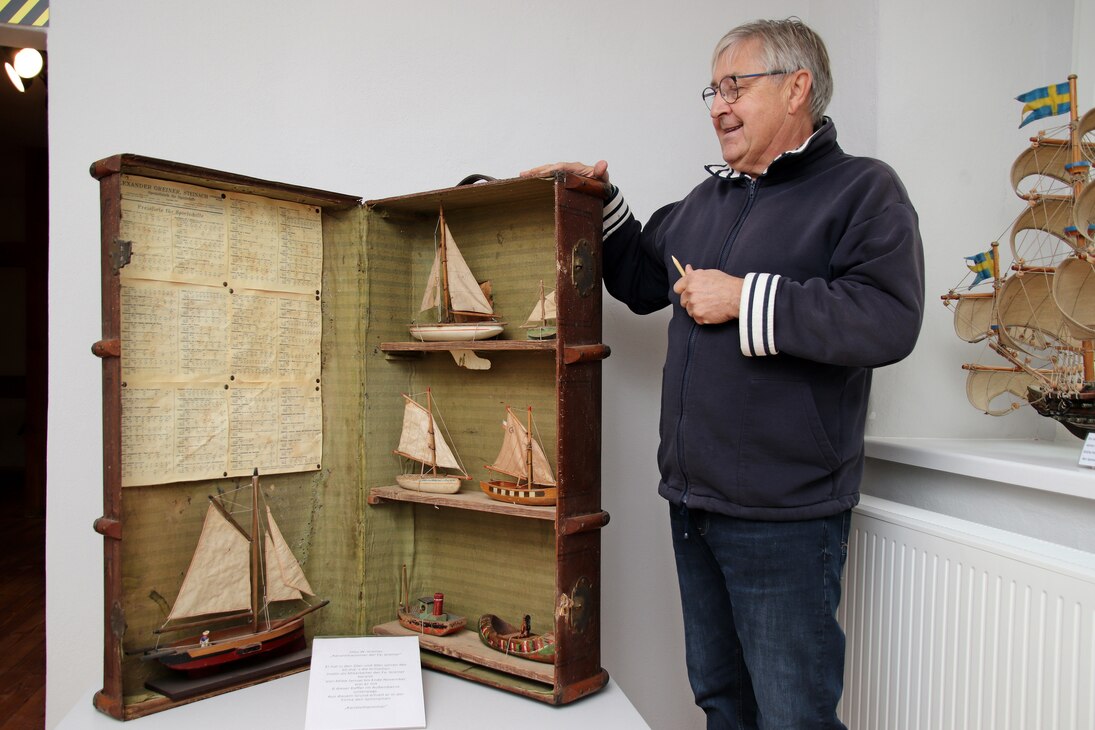 Der Museumsgründer neben einem großen geöffneten Koffer mit verschiedenen Schiffsmodellen