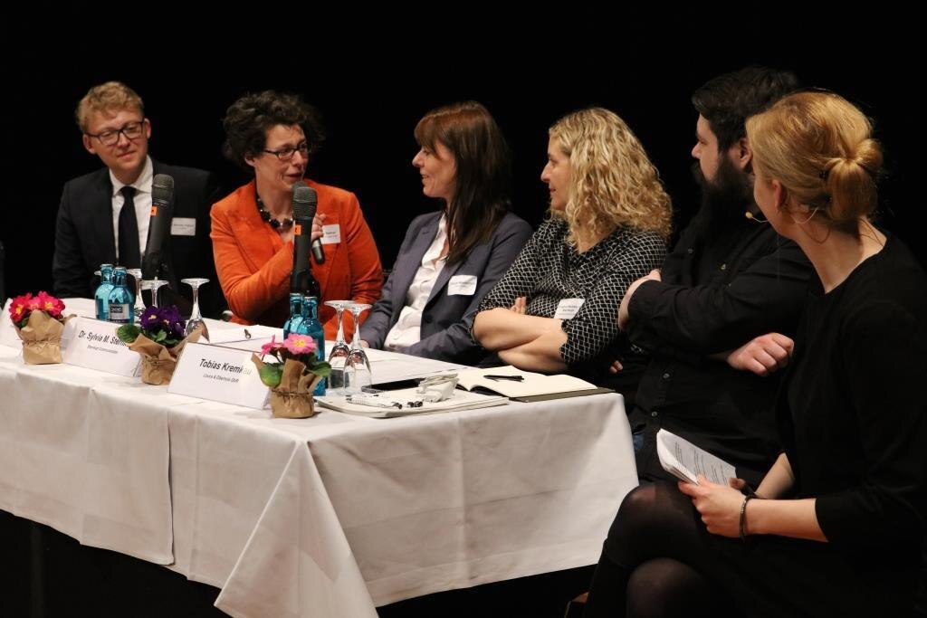 Podiumsdiskussion »Arbeit »glokal«, dezentral, vernetzt«. Von links nach rechts Dr. Norman Franchi, Sabine Gollner (am Mikrofon), Claudia Muntschick, Dr. Sylva Michèle Sternkopf, Tobias Kremkau, Moderatorin Carmen Hentschel.