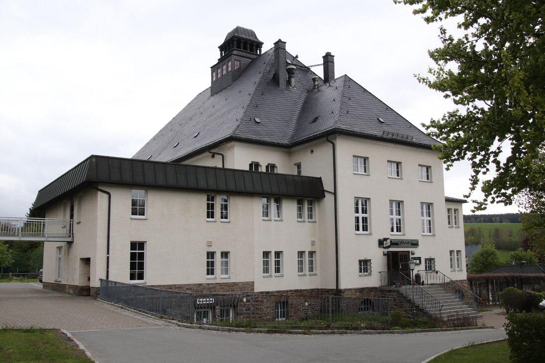 Blick auf das weiß verputzte Gebäude mit grauem Schieferdach