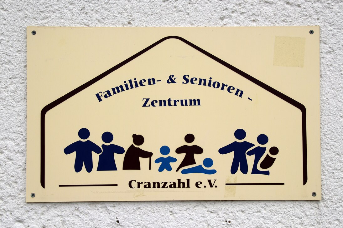 Schild an der Wand mit der Beschriftung Familien- und Seniorenzentrum Cranzahl e. V. und Vereinslogo, das stilisierte Personen aller Altersgruppen zeigt
