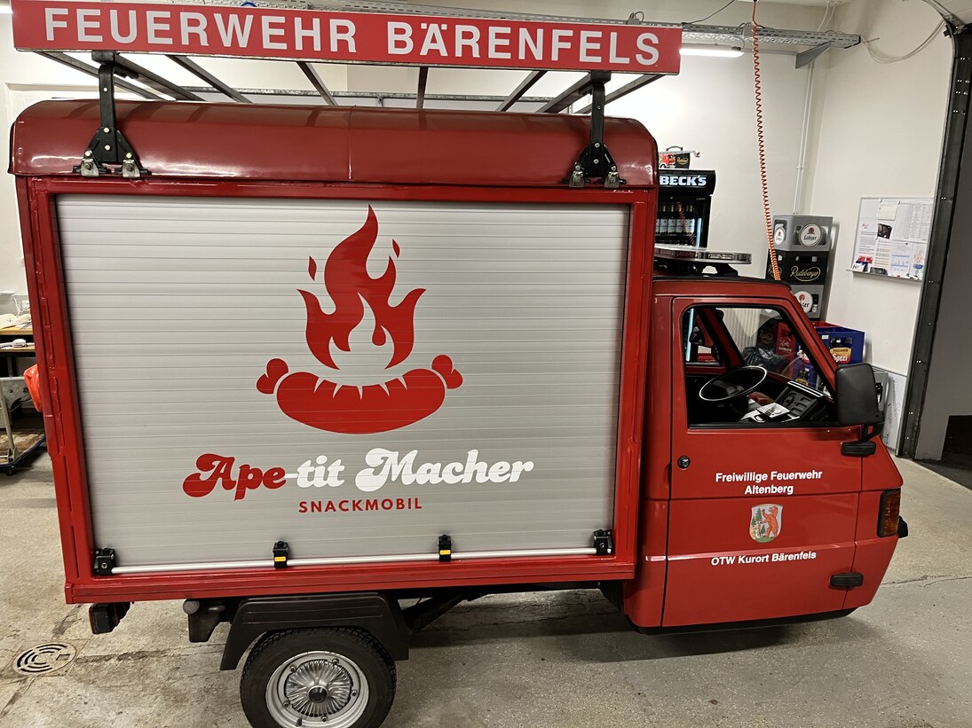 rotes italienisches Dreirad-Nutzfahrzeug Piaggo APE als Feuerwehr-Einsatzfahrzeug mit der Aufschrift "Ape-tit Macher"