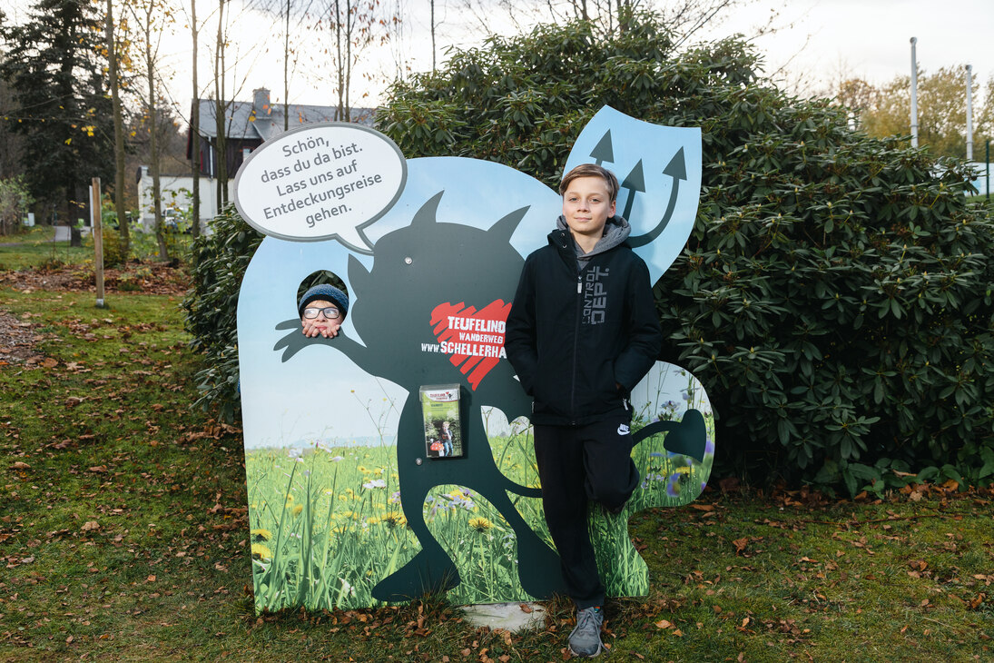 Zwei Jungen an einer Informationstafel mit der Aufschrift "Teufelino Wanderweg". Es handelt sich um den Teufelino-Kinderwanderweg in Altenberg.