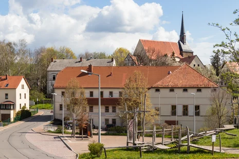 Blick auf das Gebäude der Diakoniestation Dittmannsdorf e.V., Spielplatz im Vordergrund, Kirche im Hintergrund