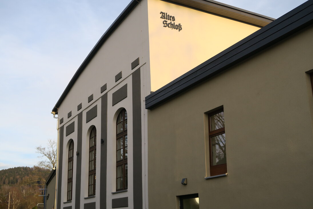 Blick auf das "Alte Schloss". Am linken Teil der Fassade sind 3 große Fenster mit Rundbogen zu sehen. An der Seite ist die Aufschrift "Altes Schloss" angebracht.