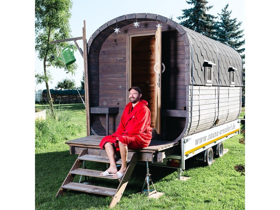 Vincent Ackermann sitzt im Bademantel vor seiner mobilen Sauna.