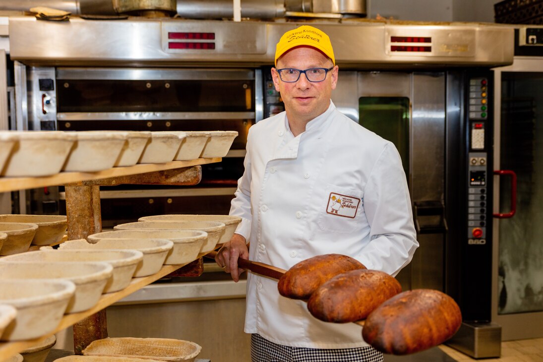 Inhaber Jörg Schürer präsentiert ein Brot, was er gerade aus dem Ofen geholt hat.