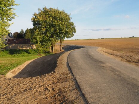 Der fertigstellte Damm mit Weg und Überflutungsrinnen