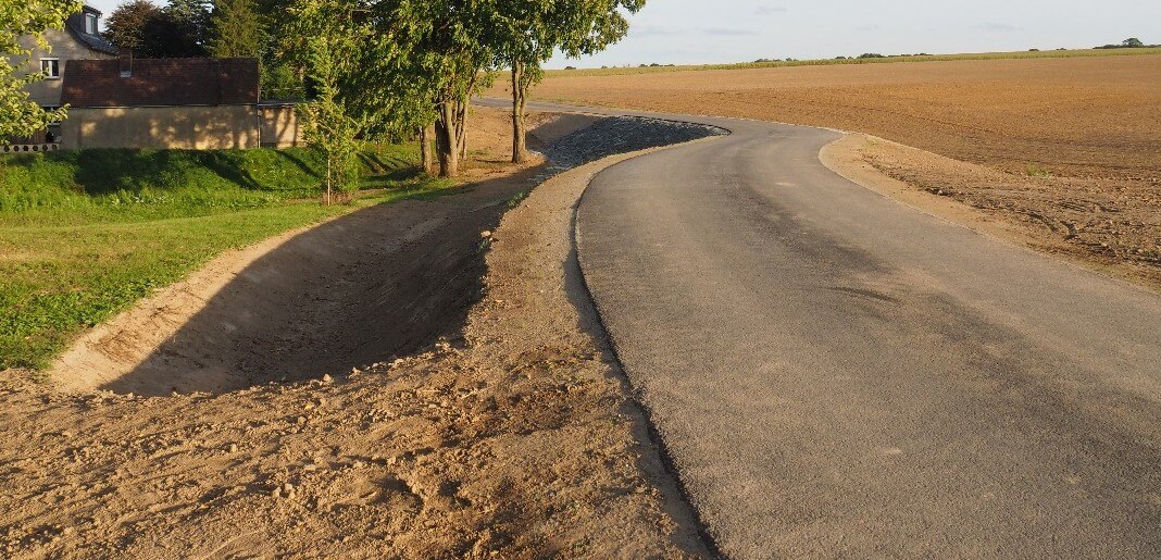 Fertiggestellter Damm mit Weg und Überflutungsrinnen