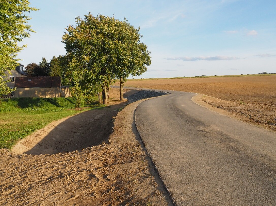 Der fertigstellte Damm mit Weg und Überflutungsrinnen