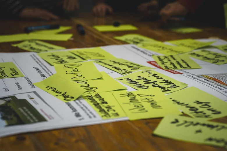 Auf einem Tisch liegt ein Formular und darauf grüne Zettel mit Ideenvorschlägen