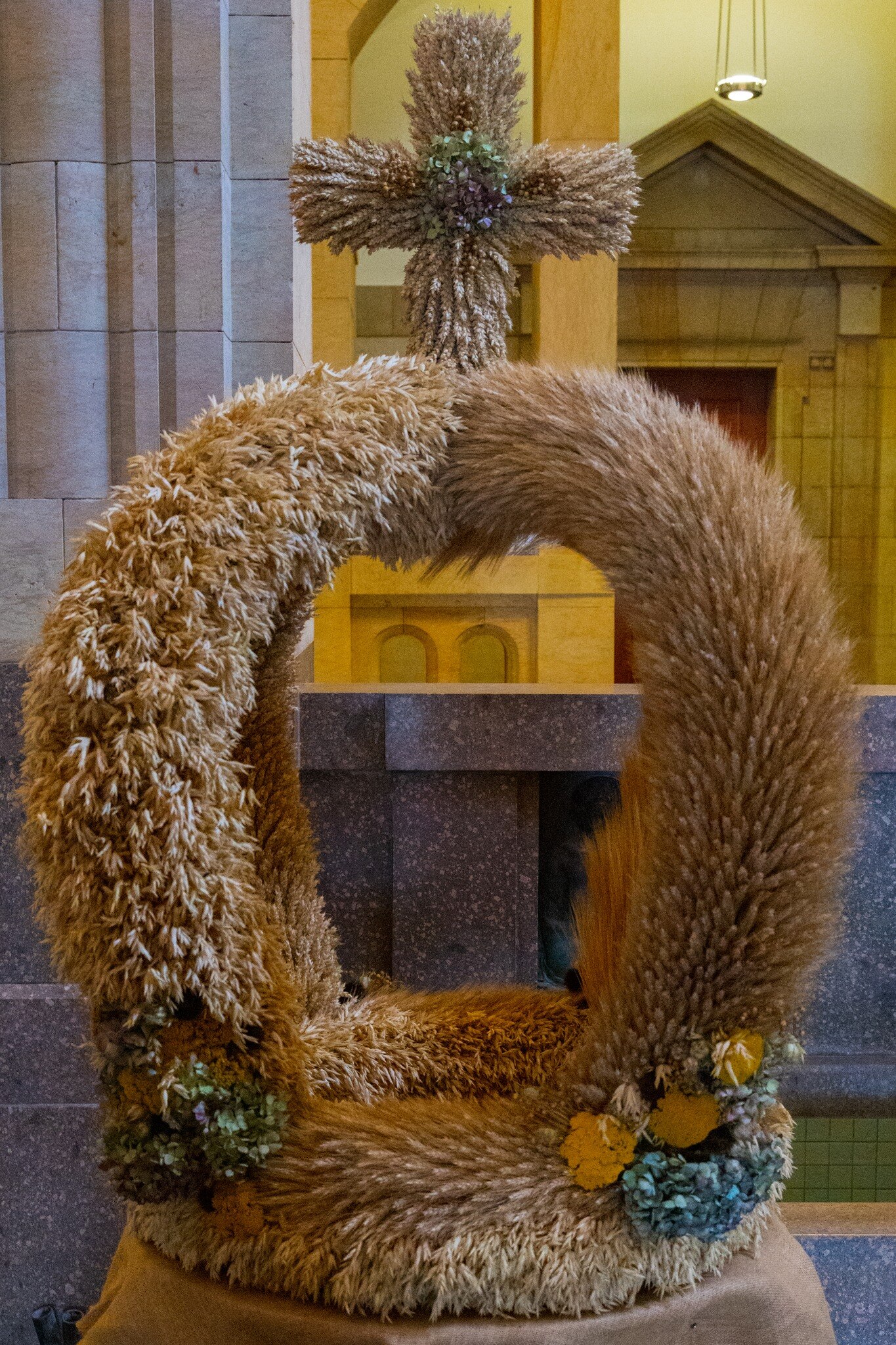 klassische Erntekrone aus Getreide, gekrönt mit Kreuz, geflochten aus Getreide und Trockenblumen