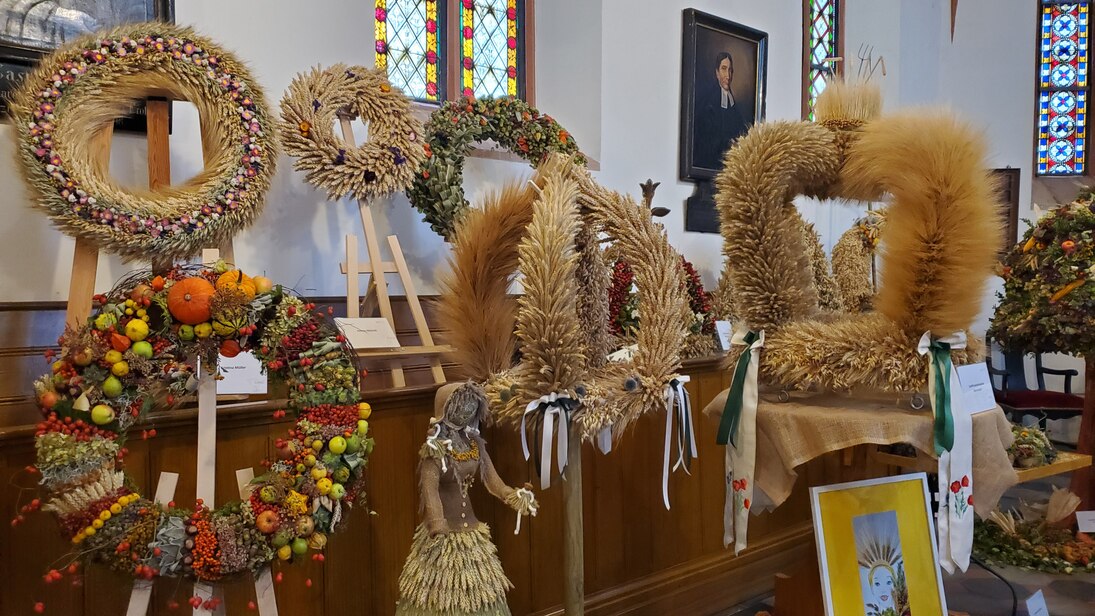 Erntekronen und Erntekränze aus Getreide, Früchten und Blumen in der Kirche
