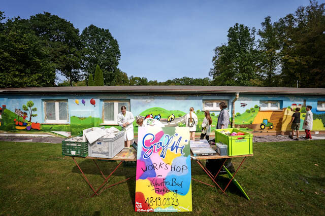 Schülergruppe arbeitet an dem Gebäude des Bades mit Spraydosen zum Thema Ernte und Landwirtwirtschaft