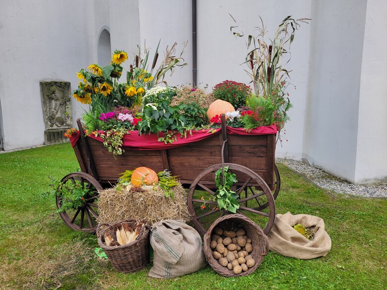 Mit Blumen und Feldfrüchten geschmückter Handwagen vor der Kirche
