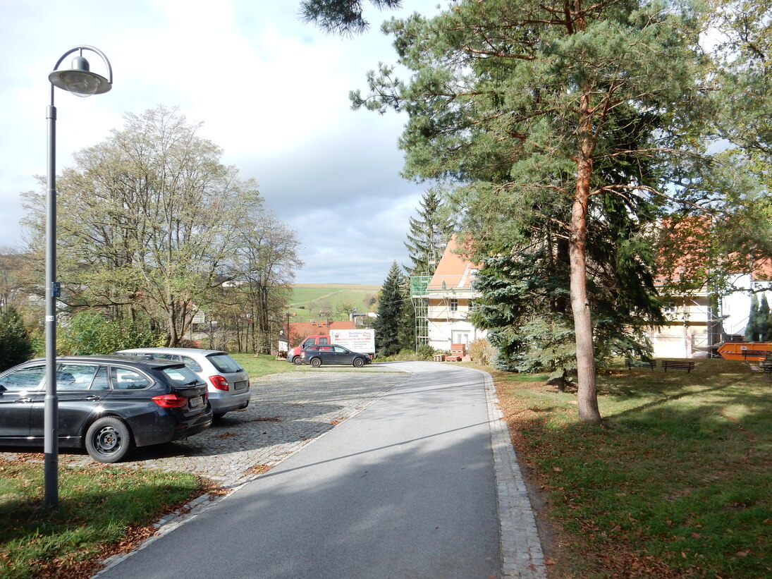 Pfarrhausweg, mit Pflaster befestigte Stellplätze für Fahrzeuge, im Vordergrund die neue Straßenbeleuchtung 