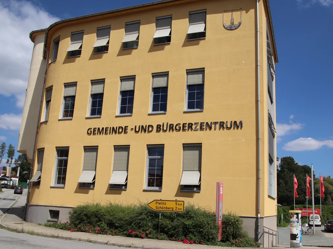 Saniertes Industriegebäude mit Fahnen und Kirchturmspitze im Hintergrund
