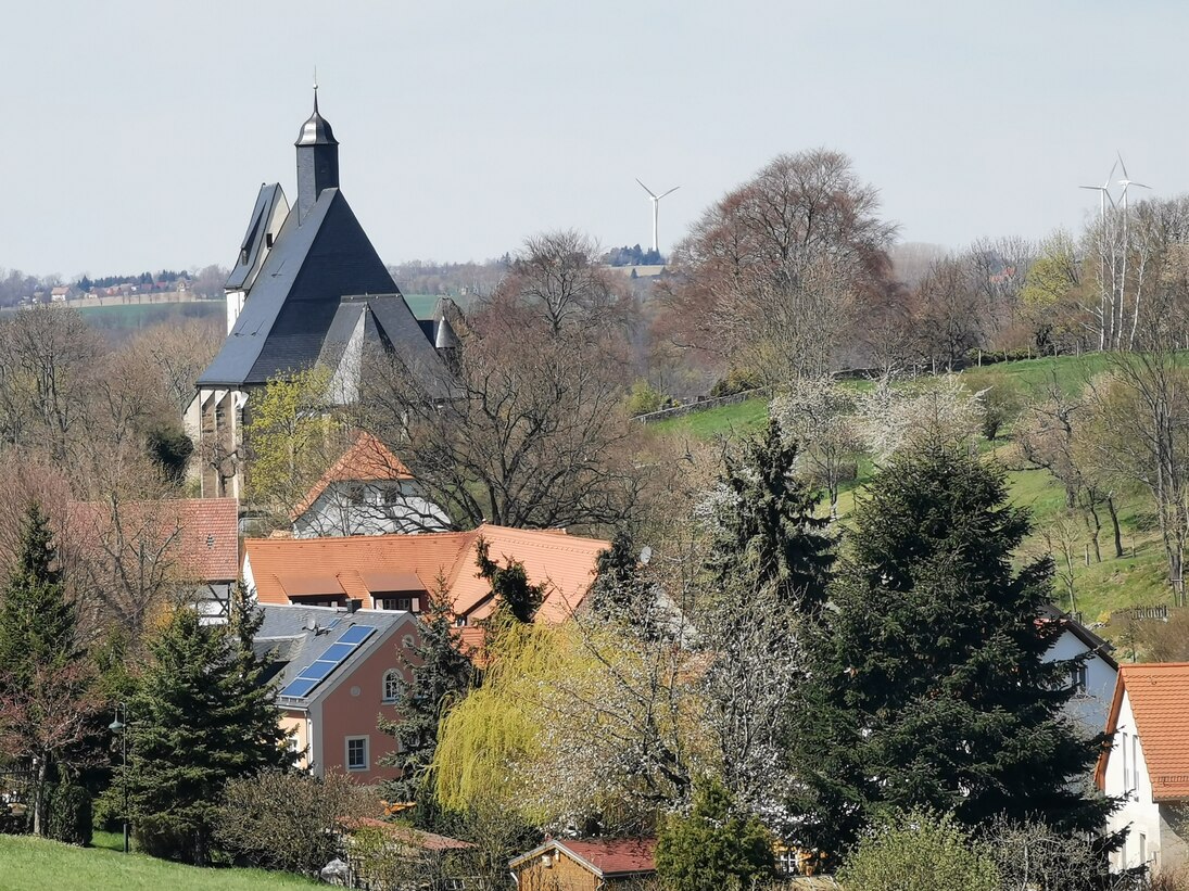 Markante Kirchensilhouette an einem ansteigenden Hang in mitten von Bäumen