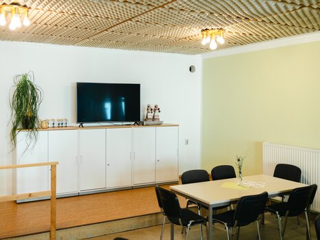 In der Seniorenbegegnungsstätte in Radeburg sind in einem Raum ein Tisch mit Stühlen, Schränke und ein Fernseher zu sehen.