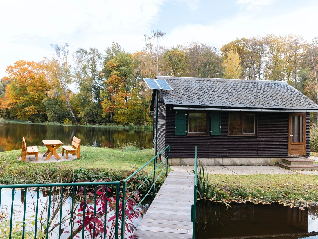 Blick auf die neue Naturschutzstation. Links davon ist eine Sitzgruppe zu sehen, im Hintergrund der See.