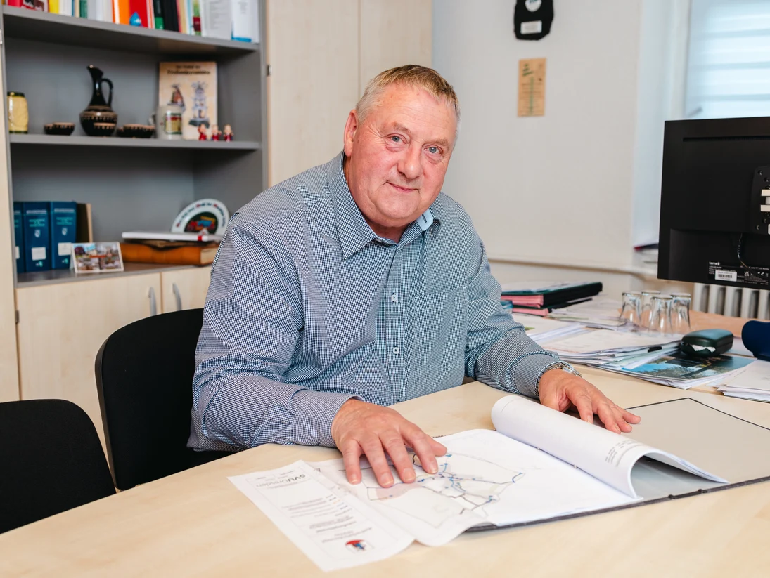 Der Bürgermeister sitzt am Schreibtisch. Vor ihm ausgebreitet liegt ein Ausschnitt des neuen Wegekonzepts.