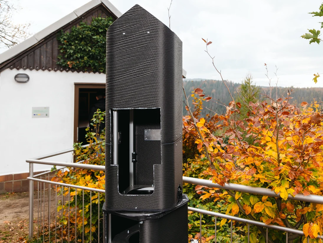 Zu sehen ist ein Häuschen im Zittauer Gebirge. Davor steht die neue Camera Obscura.