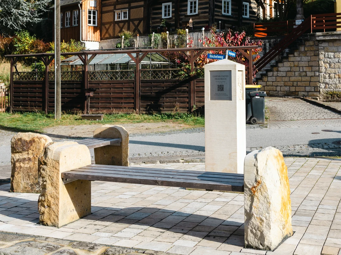 Blick auf die Casper-David-Friedrich Stele. Ringsum sind einige Bänke zur Rast zu sehen.