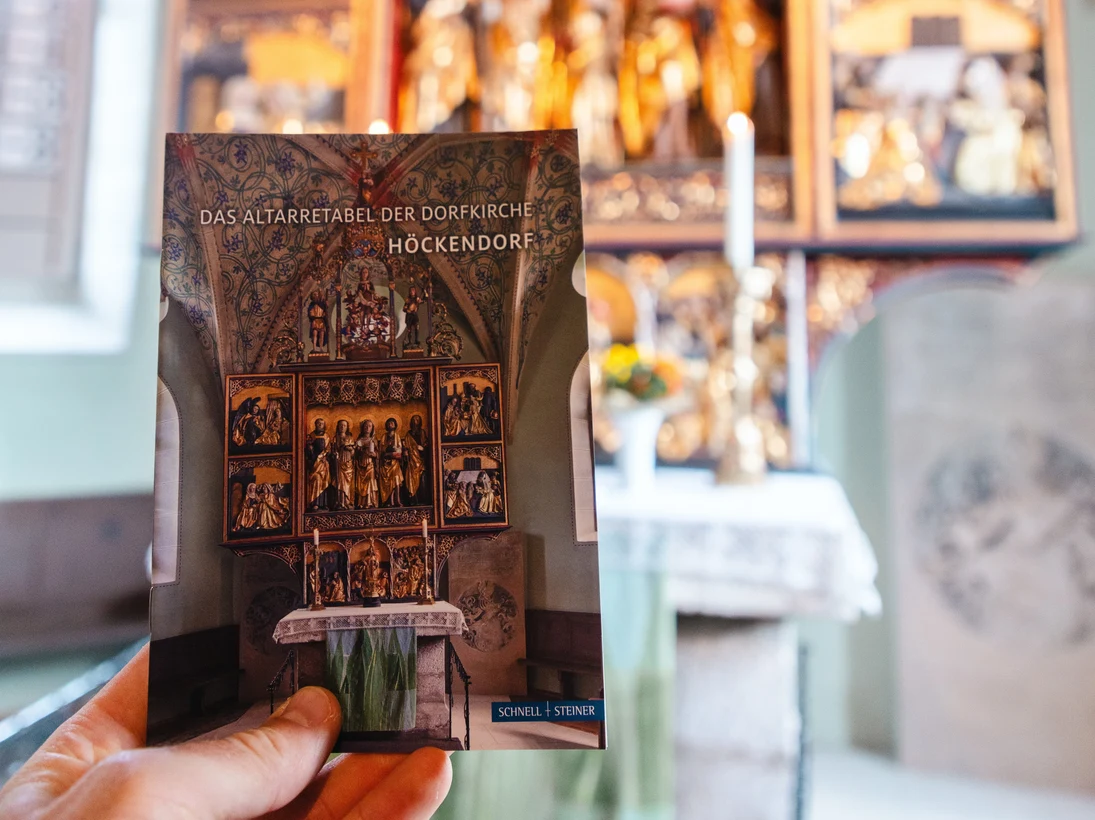 Ein Mensch hält das Altarretabel der Kirchen in Höckendorf in der Hand. Im Hintergrund ist der Altar der Kirche zu sehen.