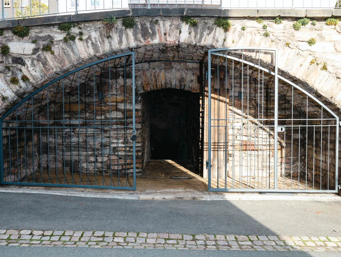 Frontalansicht auf das umgestaltete Gewölbe. Hinter einem Gitter mit offener Türe ist Platz für Ausstellungen.