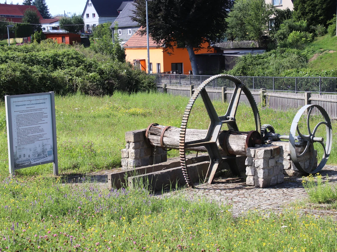 Mühlentechnik und eine Erinnerungstafel auf einer Wiese