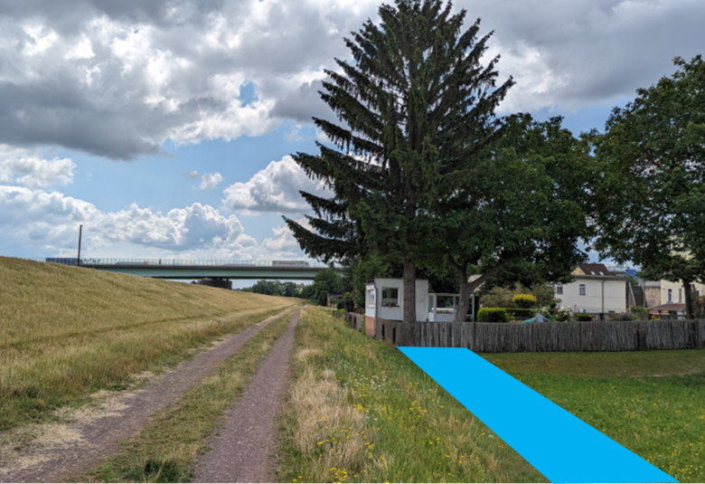 links der neue Deich, rechts ein Grundstück mit Bäumen.. Auf Höhe des Grundstücks ist ein blauer Streifen, der die Lage des gesetzlichen Deichschutzstreifens zeigt