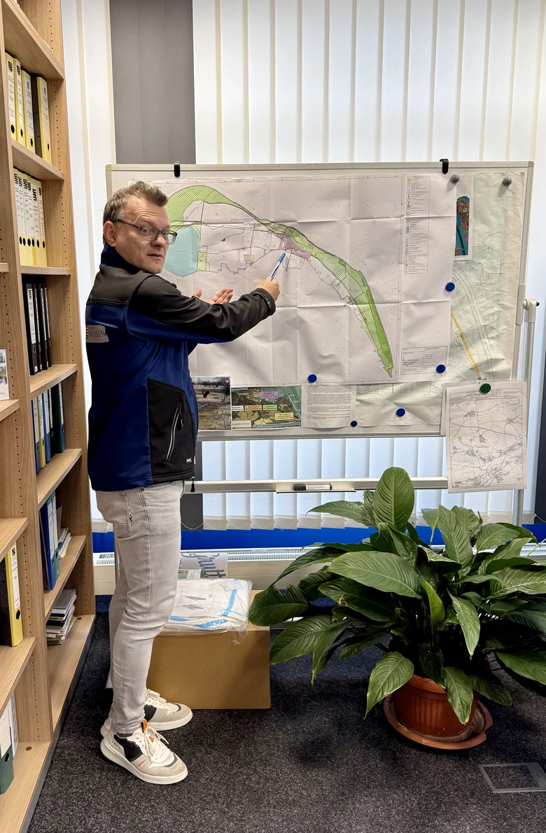ein Mann steht in seinem Büro vor einer Karte und zeigt den entsprechenden Abschnitt