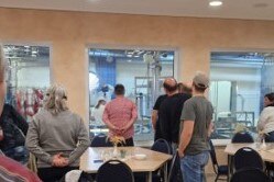 Personen schauen durch ein Fenster in die Produktionshalle
