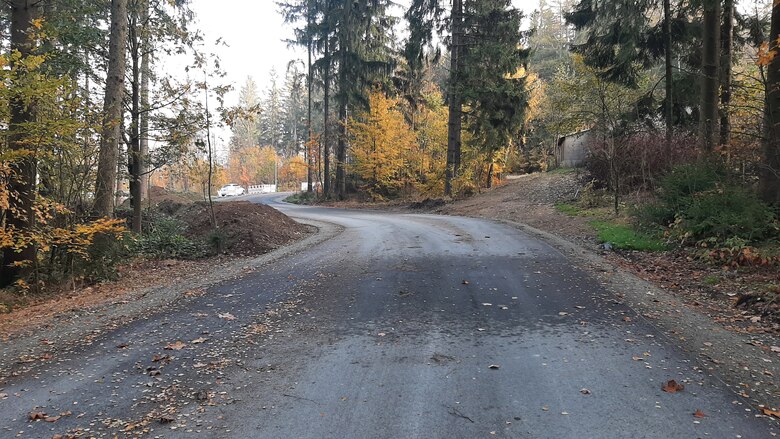 Waldweg mit neu angelegter Trasse links und aufgegebenem Abschnitt der ehemaligen Wegführung rechts, umgeben von herbstlich gefärbten Bäumen.