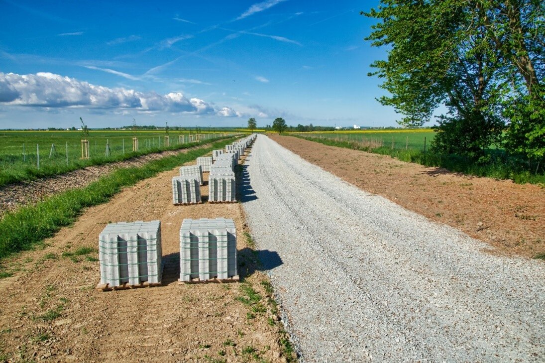 landwirtschaftlicher Weg - hier ist der Unterbau des Weges mit Kies bzw. Schotter vorbereitet. Links vom Weg stehen Stapel mit den Steinen, die für die Pflasterung vorgesehen sind.