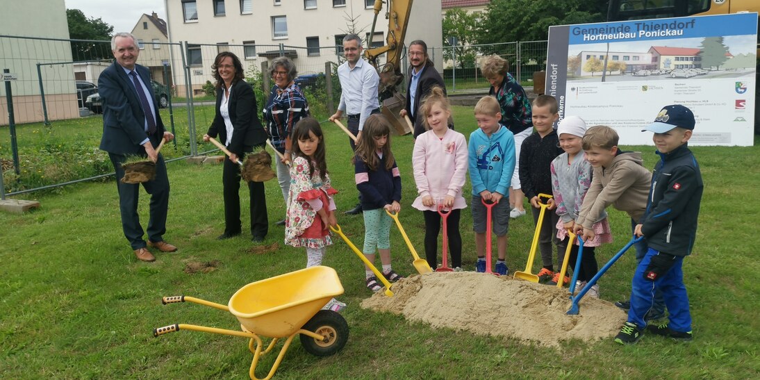 Staatsminister Schmidt, acht Kinder sowie weitere Teilnehmer beim ersten Spatenstich