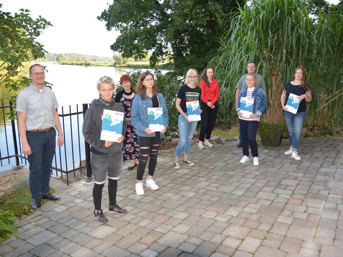 Gruppe von Jugendlichen mit ihren Zertifikaten in ihren Händen mit einer Flusslandschaft im Hintergrund